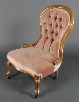 A Victorian mahogany show frame nursing chair upholstered in pink buttoned material, raised on cabriole supports