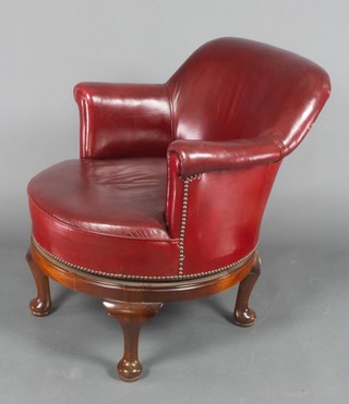 A mahogany revolving chair upholstered in red leatherette, raised on cabriole supports