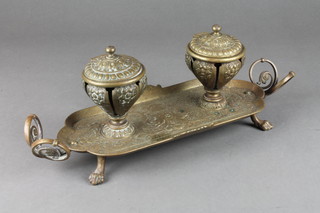 A Victorian embossed brass 2 bottle inkwell raised on an oval stepped base with paw feet 14" 