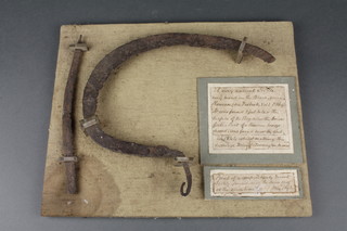 A "very ancient sickle" found 2 feet below the surface of a bog together with part of a Roman bronze sword found in 1844, mounted on a display board 