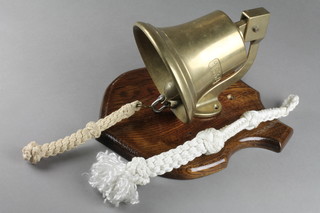 A wall mounting brass bell on an oak shield