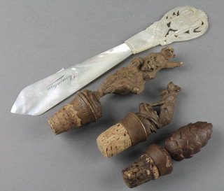 3 Black Forest carved wooden bottle stoppers in the form of 2 bears 4", a seated bear with barrel 3" and a fir cone 3" together with a pierced mother of pearl paperknife  