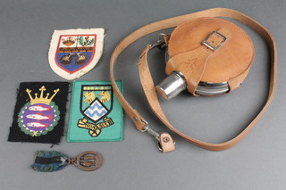 A circular chrome hip flask with leather case 5", a National Rifle Association medal, an England Boxing Association blazer badge? and 2 other cloth badges 