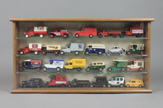An oak finished wall mounting display cabinet containing 23 various Corgi models