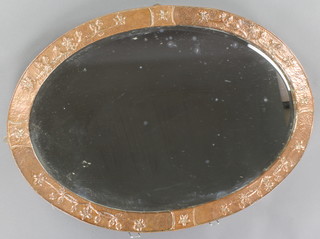 An Art Nouveau oval plate mirror contained in an embossed copper frame 24" x 34" 