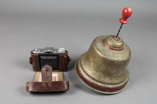 A German pressed metal spinning top in the form of a bell and a Zeiss Mettar camera 