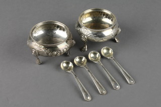 A pair of Victorian silver table salts with floral and fan decoration on hoof feet London 1881, 4 ensuite salt spoons
