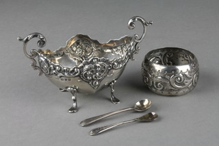 A Victorian repousse silver boat shaped table salt with scroll handles Birmingham 1899, a ditto napkin ring and 2 plated spoons