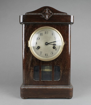 A 1930's chiming mantel clock with silvered dial and Arabic numerals contained in an arched oak case 