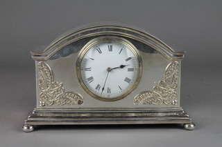 A 1930's French Art Deco 8 day timepiece with enamelled dial and Roman numerals contained in an arched silver plated case on bun feet 