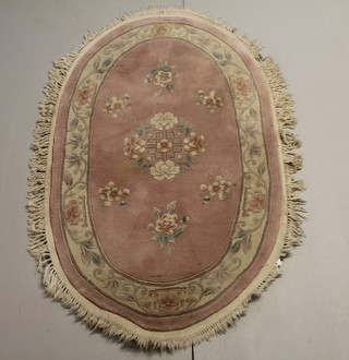 A pink ground oval Chinese rug with floral decoration 63" x 37" 
