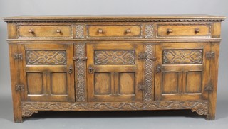 A 17th Century style carved oak dresser base fitted 3 drawers above triple cupboard enclosed by panelled doors, heavily carved throughout 36"h x 71"w x 19"d