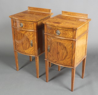 A handsome pair of Edwardian inlaid satinwood bow front bedside cabinets with raised backs and cross banded tops, fitted a drawer above a cupboard raised on square tapering supports 32"h x 15"w x 16"d