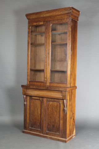 A Victorian figured walnut bookcase on cabinet, the upper section with moulded cornice, the interior fitted adjustable shelves enclosed by arched panelled doors, the base fitted 1 long drawer above a double cupboard with vitruvian scrolls to the side 83"h x 34"w x 15"d 