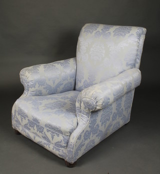 A Victorian low arm chair upholstered in blue figured floral material on bun feet 
