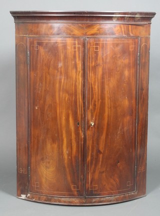 A Georgian mahogany bow front hanging corner cabinet with moulded cornice, fitted 3 shelves enclosed by panelled doors with inlaid satinwood stringing 42"h x 31"w x 21"d 
