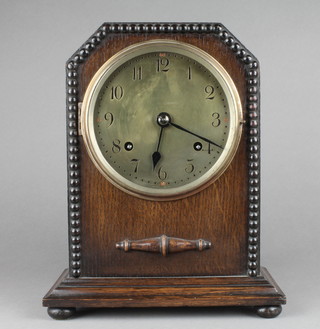 A 1930's 8 day striking mantel clock with brass dial and Arabic numerals contained in an oak arch shaped case,with XL Registered label, the interior of the door marked Eric Bragdale, 18 Dec 1934