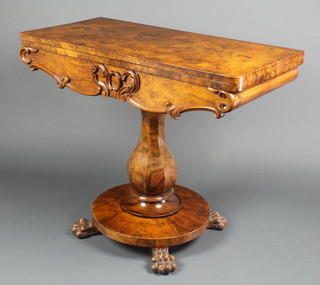 A Victorian figured walnut card table with carved apron and baluster turned column, raised on a circular base with paw feet 29"h x 35 1/2"w x 13 1/2"d