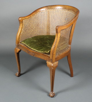 A walnut tub back single cane bergere armchair, raised on cabriole ball and claw supports 