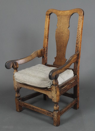 An 18th/19th Century elm open arm carver chair raised on turned and block supports 