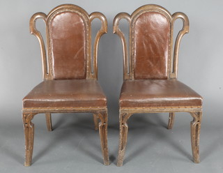 A pair of oak show frame "tulip" back dining chairs, the seats and backs upholstered in rexine and raised on sabre supports 
