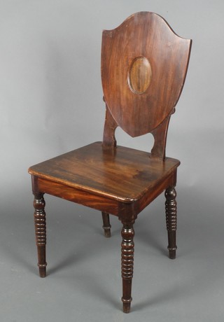 A Georgian mahogany shield back hall chair with solid seat, raised on ring turned supports 