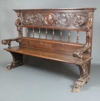 An 18th/19th Century carved oak settle, the raised back carved portraits and with bobbin turned decoration having 2 carved scrolled arms and scrolled feet 54"h x 78"w 