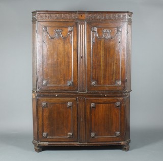 An 18th Century Continental oak cabinet with canted corners, the upper section with Grecian key cornice fitted a secret drawer, the base with parquetry interior fitted a cabinet fitted 8 short drawers enclosed by a parquetry panelled door and flanked by 2 short drawers, the interior fitted 1 long drawer enclosed by a pair of panelled doors with carved swag decoration above a brushing slide, the base fitted a cupboard enclosed by a panelled door 66"h x 48"w x 20"d 