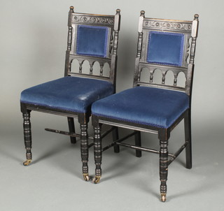 A pair of Victorian carved ebonised bedroom chairs with upholstered seats and backs and bobbin turned decoration with H framed stretcher 