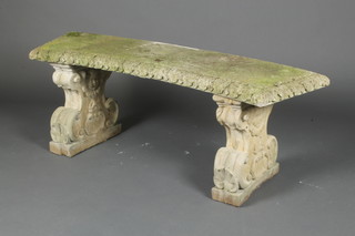 A well weathered reconstituted stone crescent shaped bench, raised on scroll ends 16"h x 84"w x 15"d 
