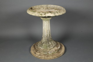 A circular reconstituted stone bird bath, raised on a stepped and reeded column 34"h x 27" diam. 