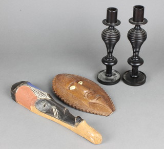 A pair of turned ebony candlesticks 9" together with 2 carved African hardwood masks 