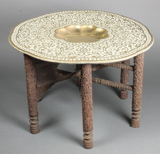 A circular Middle Eastern embossed brass tray, raised on a folding stand 21"h x 30 1/2" diam. 
