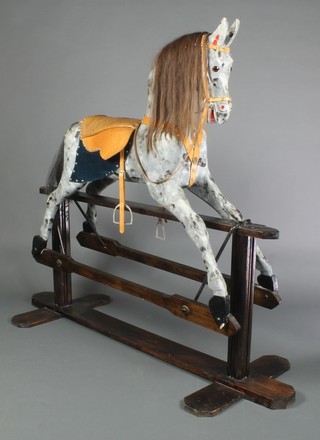 An early 20th Century dappled grey rocking horse on a treadle base, with mane, tail and leather tack 52"h x 61"l x 23"d 