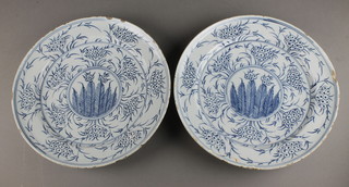 A pair of 18th Century Delft blue and white shallow plates decorated with stylised flower heads enclosing a panel of stylised feathers 13" 