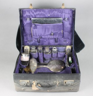 A leather toilet case comprising 5 silver mounted bottles, 4 brushes, mirror and blotter, Birmingham 1912/1939, London 1919 with outer protector