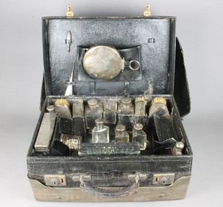 An Edwardian crocodile leather toilet case containing a silver hip flask with cup base, rectangular toilet box, cased manicure set, 8 silver topped bottles, 4 brushes, a hand mirror and blotter, London 1901/05/07/08 and Birmingham 1908 with outer protective case 