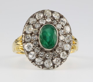 An 18ct yellow gold emerald and diamond cluster ring, the centre emerald approx 0.75ct surrounded by 2 bands of 32 brilliant cut diamonds, size N