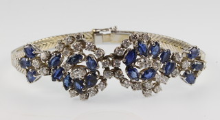 An 18ct white gold diamond and sapphire scroll bracelet, 26 grams