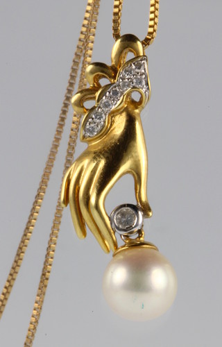 An 18ct gold yellow diamond pearl hand pendant on a ditto chain