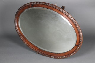 An Edwardian oval bevelled plate wall mirror contained in a carved mahogany frame 28" x 41"