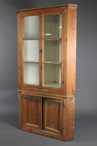 A 19th Century pine double corner cabinet, the upper section with moulded cornice and Grecian key decoration, fitted shelves enclosed by glazed panelled doors, the lower section enclosed by double cupboard 78"h x 43"w x 23"d 