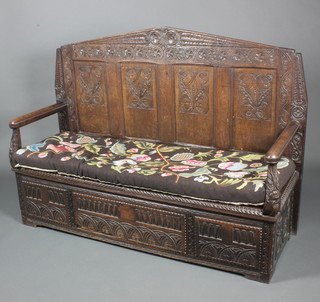 A carved oak settle with raised back and Berlin wool work swab, the base fitted a drawer 43"h x 60"w x 21"d (made up) 