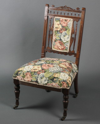 An Edwardian carved walnut bedroom chair with bobbin turned decoration, upholstered seat and back, raised on turned supports 