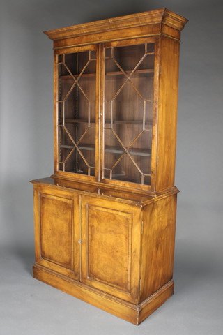 A Queen Anne style figured walnut bookcase on cabinet, the upper section with moulded cornice enclosed by astragal glazed panelled doors, the base enclosed by a panelled door, 77"h x 40"w x 19"d 