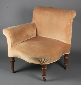 A Victorian corner armchair, upholstered in peach coloured material, raised on turned supports 