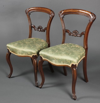 A pair of Victorian rosewood balloon back dining chairs with carved mid rails and seats of serpentine outline, raised on cabriole supports 