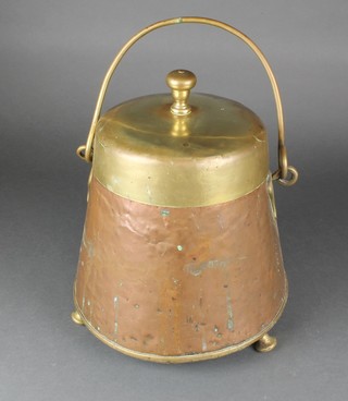 A cylindrical copper and brass coal bin with swing handle, raised on bun feet 13" 