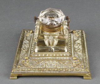 A Victorian square cut glass inkwell with hinged lid, raised on a square cast brass base (inkwell lid f)