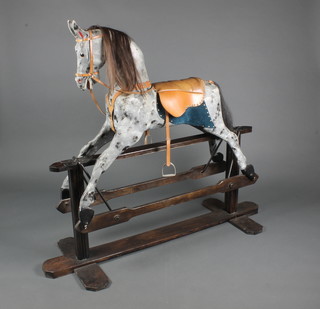 An early 20th Century dappled grey rocking horse on a treadle base, with mane, tail and leather tack 52"h x 61"l x 23"d 